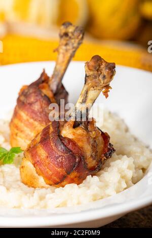 Hähnchenschenkel mit Speck auf Risotto Stockfoto