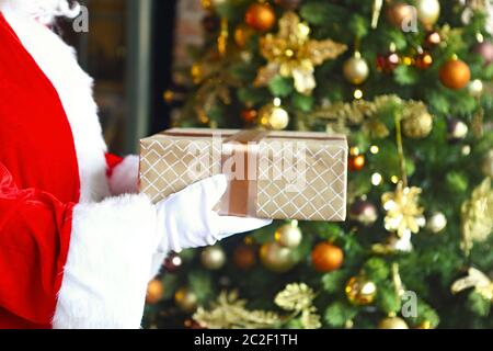 Santa Claus heimlich setzen Geschenkbox am Weihnachtsbaum Stockfoto