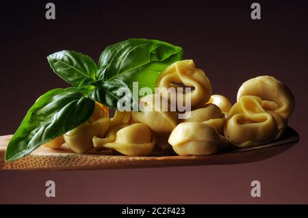 Tortellini mit Basilikum auf einem Löffel Stockfoto