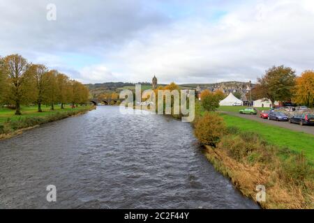 PEEBLES, SCHOTTLAND - 20. OKTOBER 2019: Blick auf den Fluss Tweed mit Bäumen in Herbstfarben und Peebles Old Parish Church Tower in der Ferne Stockfoto