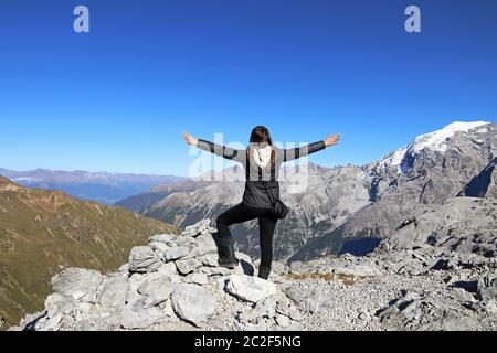 Eine Frau in den Bergen streckt ihre Arme vor Freude aus. Spaß beim Bergsteigen Stockfoto