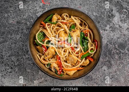 Hähnchen unter Rühren mit Gemüse Sojasause und Sesam im Wok braten. Traditionelle asiatische Küche. Draufsicht mit Kopierplatz auf Steintisch. Stockfoto