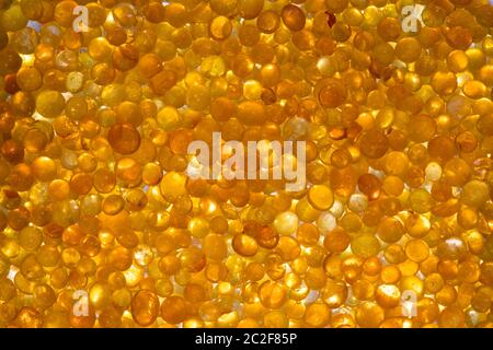 Nahaufnahme des Orangensilicagels. Goldene, durchscheinende Perlen mit glänzendem Licht. Abstrakter goldener Hintergrund Stockfoto