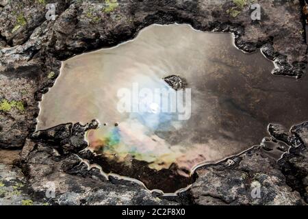 Öliges Wasserloch im Wasser der steinigen Landschaft. Stockfoto