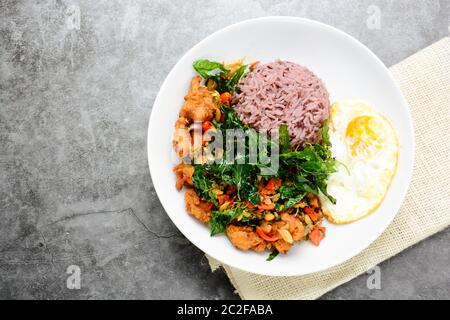 Knusprige Hähnchen mit grünem Basilikum gekocht, serviert mit gedämpftem Reis und Spiegelei, heiß und würzig Gericht w Stockfoto