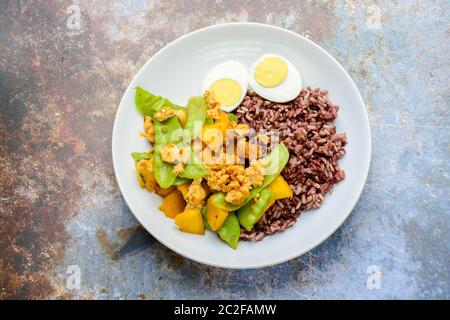 Pfannengerichte Zuckerschoten mit Kürbis und Huhn, serviert mit braunem Reis und gekochtem Ei Stockfoto