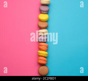 Runde bunte Macarons gebacken mit Sahne liegen in einer Linie auf einem rosa Hintergrund blau, Flach, kopieren Raum Stockfoto