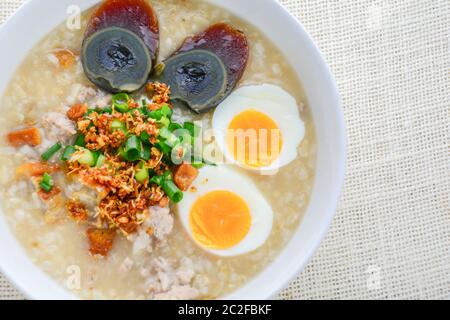 Congee, Reisbrei mit gehacktem Schweinefleisch, gekochtem Ei und Century Egg, super zum Frühstück. Stockfoto