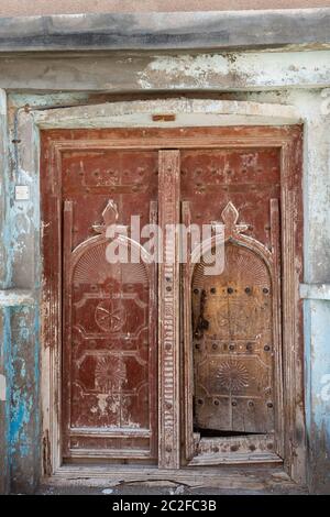 Traditionelle alte rötlich-braune Holztür in der Stadt Al Ayjah in der Nähe von Sur, Oman Stockfoto