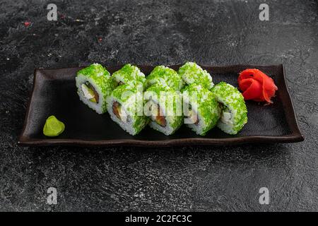 Sushi-Brötchen mit Tobiko Green Caviar, Frischkäse und Fisch auf schwarzem Holztisch Hintergrund Stockfoto