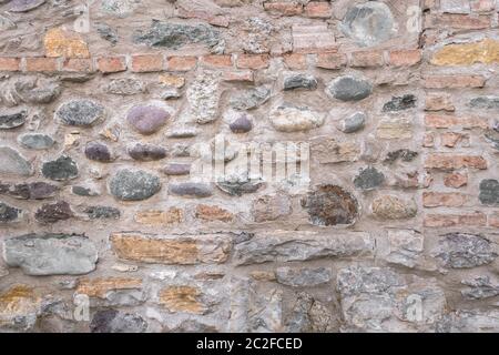 Alte Mauer aus unregelmässigen Steinen mit warmen Farben Stockfoto