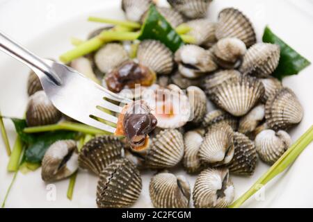 Gekochte Herzmuscheln oder Jakobsmuscheln mit Meeresfrüchtesoße Stockfoto