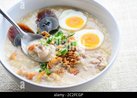 Congee, Reisbrei mit gehacktem Schweinefleisch, gekochtem Ei und Century Egg, super zum Frühstück. Stockfoto