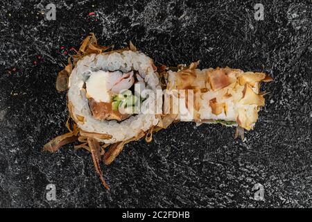 Sushi-Rolle mit Lachs, Käse, Gurken und Aal Rasur isoliert auf einem schwarzen Hintergrund mit Reflexion Stockfoto