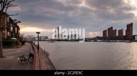 Sonnenstrahlen brechen durch Wolken über dem Lots Road Power Station und dem World's End Estate an Chelsea's River Thames Waterfront in West London. Stockfoto