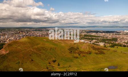 Salisbury Crags, Holyrood Park und das Stadtbild von Edinburgh sind unterhalb von Arthur's Seat angeordnet. Stockfoto