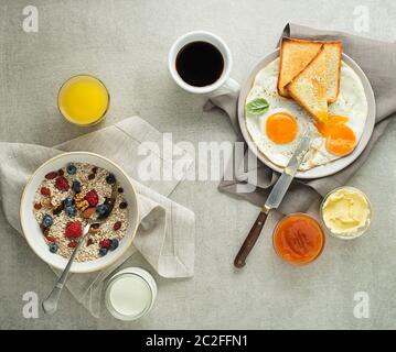 Frühstück serviert mit Haferflocken und Obst, Spiegeleier mit Brot und Marmelade mit Butter auf dem Tisch Ansicht von oben. Heathy Frühstück essen Stockfoto