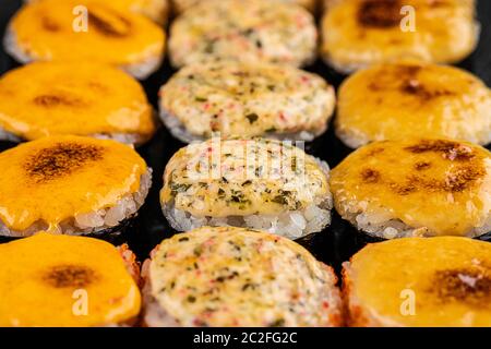 Gebackene Sushi-Brötchen mit Wasabi und Ingwer auf schwarzem Hintergrund. Japanische orientalische Küche Stockfoto