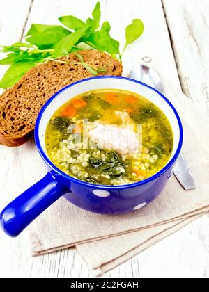 Schweinerippchen Suppe mit Couscous und Spinat in eine blaue Schale auf dem Handtuch, Brot auf Holzbrett Hintergrund Stockfoto