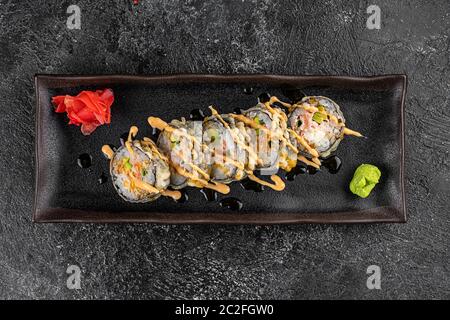 Gebackene Sushi-Brötchen mit Wasabi und Ingwer auf schwarzem Hintergrund. Japanische orientalische Küche Stockfoto