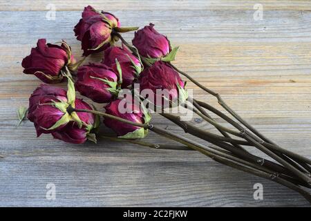 Bouquet von verwelkten Rosen auf einem hölzernen Hintergrund Stockfoto