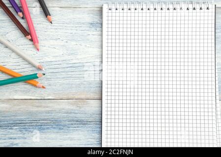 Bleistifte und ein Notizbuch aus Papier auf einem hellblauen alten hölzernen Hintergrund. top anzeigen. Flach Stockfoto