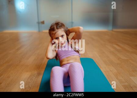 Kleines Mädchen tun Presse Übung auf Matte im Fitnessstudio Stockfoto