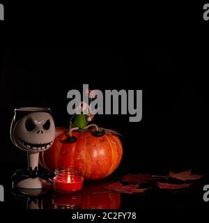 Halloween Stillleben mit Kürbis, Herbstblättern, Kerze und Hexe auf schwarzem Hintergrund. Halloween Hintergrund Stockfoto