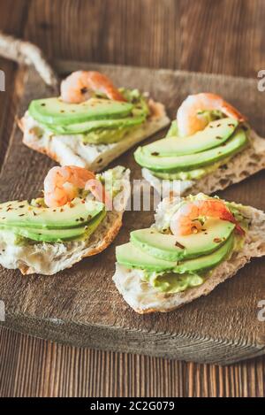 Sandwiches mit Guacamole, in Scheiben Avocado und Garnelen auf der Holzplatte Stockfoto