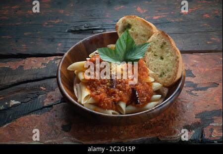 Pasta mit Tomatensauce mit Knoblauchbrot auf rustikalem Holzhintergrund isoliert Stockfoto