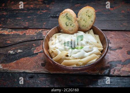 Vier Käse Pasta mit Knoblauchbrot isoliert auf rustikalem Holzhintergrund Stockfoto