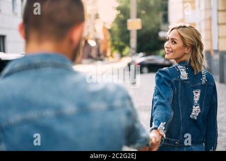 Schöne junge Frau, die auf der Straße geht und Mann von Hand hält Stockfoto