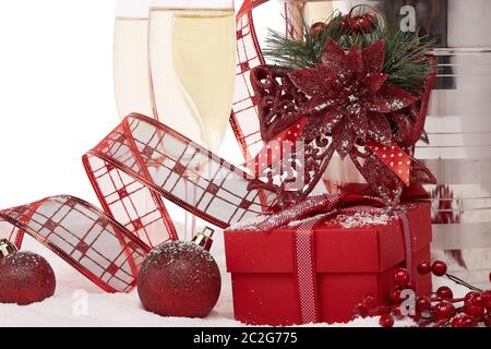 Stillleben mit Champagner-Flasche in einem Eimer mit Eis, zwei volle Sektflöten, Geschenkbox und Weihnachtsschmuck stehen. Weihnachten und Neujahr BA Stockfoto