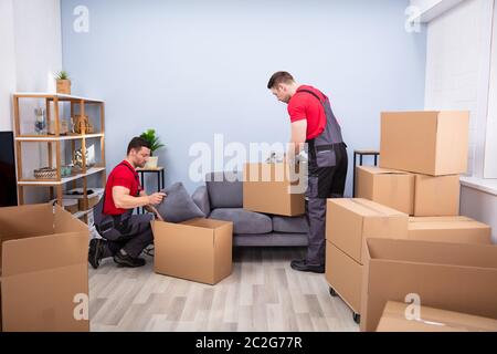 Zwei junge Movers in Uniform Kommissionierung und das Inverkehrbringen von Produkten in der Kartons Stockfoto