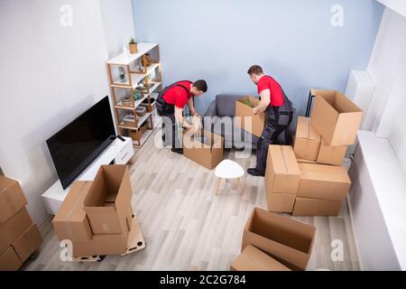 Zwei junge Movers in Uniform Kommissionierung und das Inverkehrbringen von Produkten in der Kartons Stockfoto