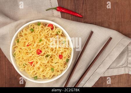 Ramen Nudeln, Schuß von oben auf einen dunklen Holzmöbeln im Landhausstil Hintergrund mit rotem Pfeffer, Stäbchen, und einen Platz für Text Stockfoto