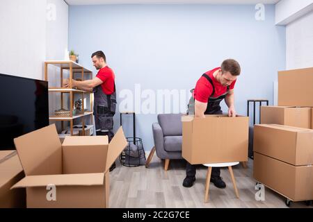 Zwei junge Movers in Uniform Kommissionierung und das Inverkehrbringen von Produkten in der Kartons Stockfoto