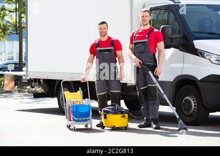 Zwei junge männliche Hausmeister mit der Reinigung der Ausrüstung gegen Lkw auf der Straße Stockfoto