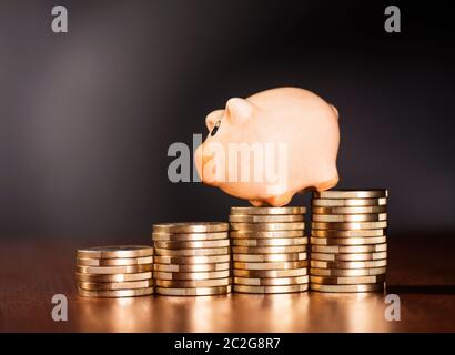 Piggy Bank stehend auf Haufen von Münzen. Stockfoto