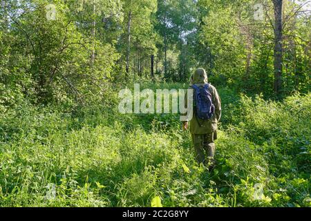 Aktiver Mann in Moskitoanzug mit Rucksack beim Wandern in einem sibirischen Wald, Russland. Alleinreisen, Lifestyle, inländisches Tourismuskonzept Stockfoto