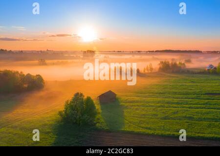 Nebel Morgen über der Ebene und Flußflut der Wiese in der Nähe eines ländlichen Dorfes mit einem Haus, Luftbild Landschaft Stockfoto