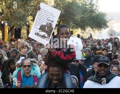 Austin Texas, USA, Januar 18 2016: Der junge Schwarze mit einem Bild von Dr. Martin Luther King Jr. sitzt während der Rallye im Texas Capitol auf den Schultern des Schwarzen Mannes bei den Feiertagsveranstaltungen von Martin Luther King Jr. ©Bob Daemmrich Stockfoto