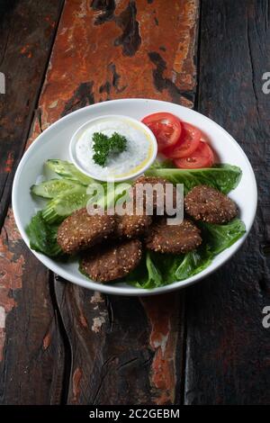 Falafel, vegan geröstete Kichererbsen-Patties mit Knoblauch-Joghurt-Sauce auf rustikalem Holztisch isoliert Stockfoto