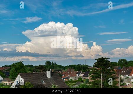 Ungewöhnliche Anordnung großer Wolken am blauen Himmel über der Stadt. Stockfoto