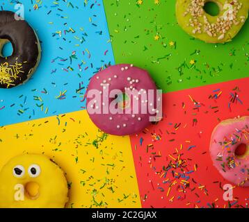 Runde Donuts mit verschiedenen Füllungen und Streuseln auf eine abstrakte Farbe Hintergrund mit festlichen Dekor Stockfoto