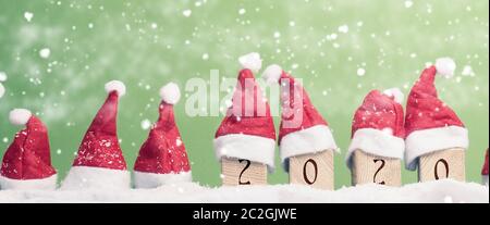 Viele Hüte von Santa in einer Reihe mit Schnee, Weihnachten Hintergrund, Panoramaaussicht Stockfoto