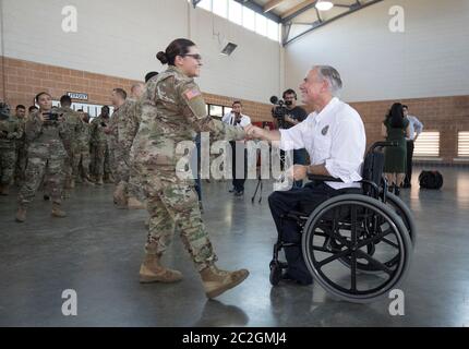 Weslaco, Texas, USA, 12. April 2018: Texas Gov. Greg Abbott begrüßt ein Mitglied der Nationalgarde in einem Waffenlager der Nationalgarde im äußersten Süden von Texas, wo sich die Truppen auf den Einsatz an der Grenze zwischen Texas und Mexiko vorbereiten. Die Soldaten werden bei der Bekämpfung der illegalen Einwanderung an der Südgrenze der Vereinigten Staaten eine unterstützende Rolle bei der Bundes- und Staatspolizei spielen. ©Bob Daemmrich Stockfoto
