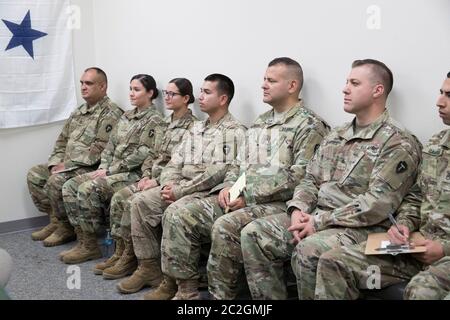 Weslaco, Texas 12. April 2018: Truppen sitzen auf einer Bank in einem Waffenlager der Nationalgarde im äußersten Süden von Texas, während sie ermutigende Worte von Gouverneur Greg Abbott hören, während sie sich auf den Einsatz an der Grenze zwischen Texas und Mexiko vorbereiten. Die Soldaten werden eine unterstützende Rolle bei der Bundesgrenzpolizei und den Staatspolizisten spielen, die versuchen, die illegale Einwanderung an der Südgrenze der Vereinigten Staaten zu verlangsamen. ©Bob Daemmrich Stockfoto