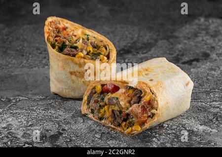 Burrito und Shawarma Wraps mit Rindfleisch und Schweinefleisch Gemüse auf Holztisch auf schwarzem Hintergrund Stockfoto