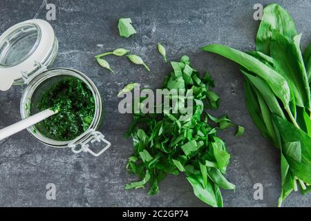 Frischer grüner Bärlauch und ein Glas mit Pesto und einigen Knospen. Draufsicht. Stockfoto